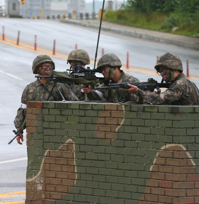 Troops stand guard at a checkpoint in Goseong, Gangwon Province, Monday in an operation to capture a heavily armed runaway sergeant, who killed five soldiers and wounded seven in a shooting spree Saturday.   Yonhap