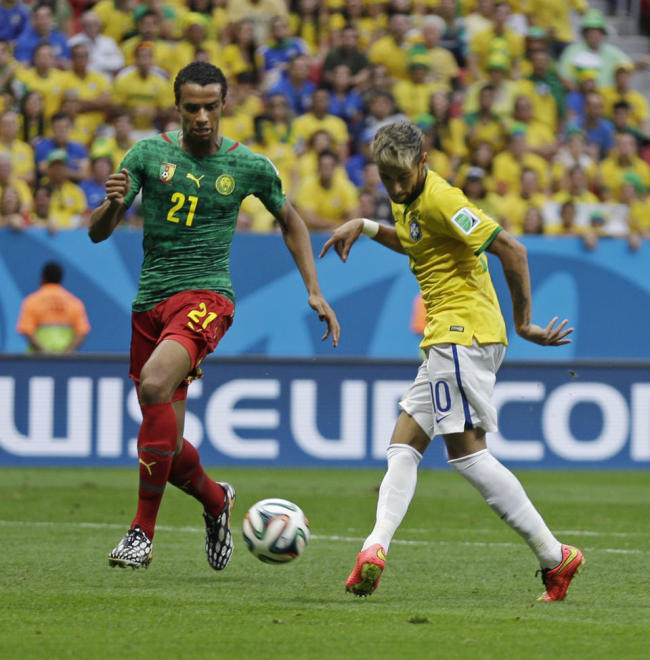 Brazil's Neymar kicks the ball past Cameroon's Joel Matip to score his side's first goal during the group A World Cup soccer match between Cameroon and Brazil at the Estadio Nacional in Brasilia, Brazil, Monday. (AP)