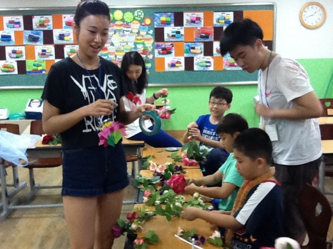 Volunteers help underprivileged children make flower bouquets at last year’s Mustard Seed English Camp.   Mustard Seed
