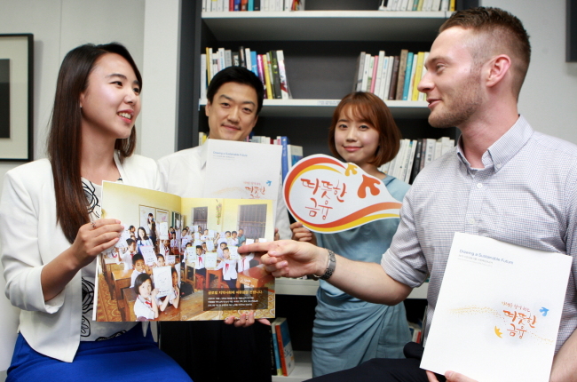 Shinhan Financial Group employees display the group’s annual CSR report for 2013, titled “Compassionate Finance.”   Shinhan Financial Group