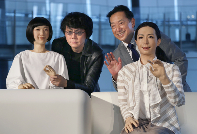 Japanese android expert Hiroshi Ishiguro (second from left) and National Museum of Emerging Science and Innovation Miraikan Chief Executive Director Mamoru Mohri (second from right) pose with a female-announcer robot called Otonaroid (right) and a girl robot called Kodomoroid during a press unveiling of the museum’s new guides in Tokyo Tuesday.   AP-Yonhap