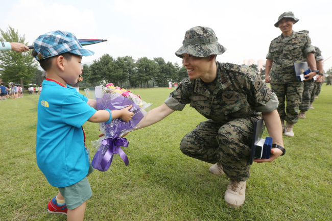 <YONHAP PHOTO-1466> '아들아 반갑다' (서울=연합뉴스) 서명곤 기자 = 27일 오후 서울 송파구 거여동 특수전사령부에서 열린 오쉬노부대 해단식에서 조대현 대위가 아들로부터 꽃다발을 받고 있다. 오쉬노 부대는 아프가니스탄의 재건을 돕기 위해 파견한 지방재건팀(PRT)을 보호하기 위해 지난 2010년 7월부터 파견돼 활동을 해오다 PRT 임무 종료와 함께 철수했다. 2014.6.27 seephoto@yna.co.kr/2014-06-27 14:52:42/ <저작권자 ⓒ 1980-2014 ㈜연합뉴스. 무단 전재 재배포 금지.>
