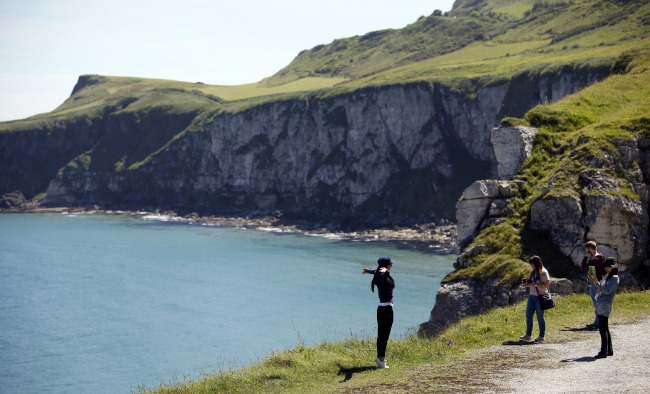 Tourists pose for photographs on the North Antrim Coast close to Carrick-a-Rede Rope Bridge and Larrybane headland. Larrybane was the dramatic spot chosen for Renly Baratheon’s camp in Season 2 of “Game of Thrones.” (AP-Yonhap)