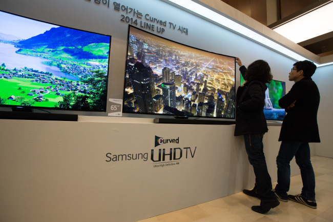 A visitor touches Samsung Electronics’ curved Ultra High Definition television displayed at a media event in Seoul in February.   Bloomberg