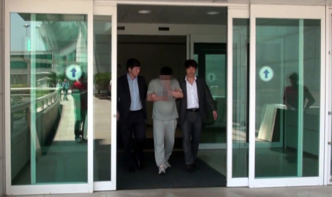Murder suspect Paeng (center) is escorted by police officers on May 22.   Yonhap