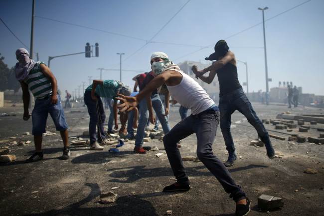 Palestinian protesters throw stones toward Israeli police in Arab East Jerusalem on Thursday.   AFP-Yonhap