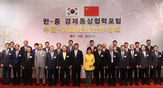 President Park Geun-hye (front, seventh from right) poses with her Chinese counterpart Xi Jinping (front, eighth from right) and business representatives from South Korea and China at a forum held at Hotel Shilla in Seoul on Friday.   Yonhap
