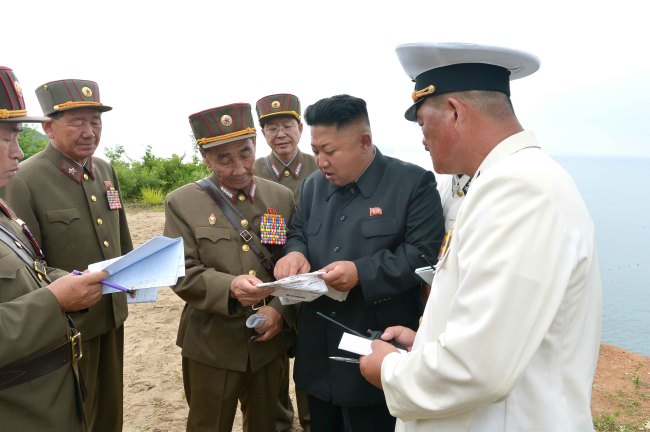 North Korean leader Kim Jong-un (second from right) and Byon In-son (fourth from right), the director of operations at the military’s General Staff, look at a document detailing striking targets during his visit to an amphibious landing exercise last Friday. If magnified, the mission to strike Spike missile units on South Korea’s border islands can be seen in the document.   Yonhap