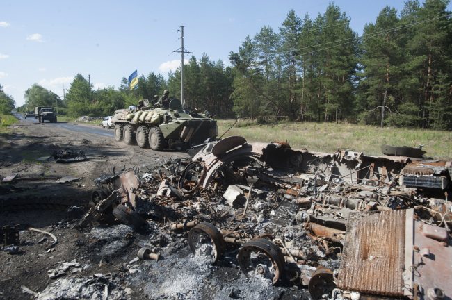 Ukrainian troops ride past a wrecked armored personnel carrier at the checkpoint in Krasnyi Lyman, eastern Ukraine, Saturday.   AP-Yonhap