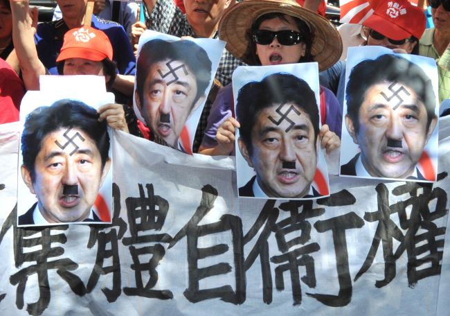 Protesters chant slogans, display Japanese military flags and portraits of Prime Minister Shinzo Abe and a banner that reads “Don’t forget Marco Polo Incident, Maintain peace in Asia” during a demonstration in front of Japan’s de facto embassy in Taipei on Monday.   AFP-Yonhap