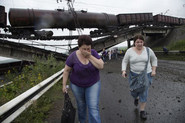 People walk under a destroyed railroad bridge over a main road near the village of Novobakhmutivka, 20 kilometers north from the city of Donetsk, eastern Ukraine, Monday.   AP-Yonhap