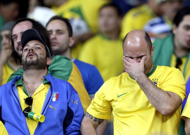 Brazil supporters react after Germany defeated Brazil 7-1 to advance to the finals during the World Cup semifinal at the Mineirao Stadium in Belo Horizonte, Brazil, Tuesday. (Related stories on Pages 2, 20)    AP-Yonhap