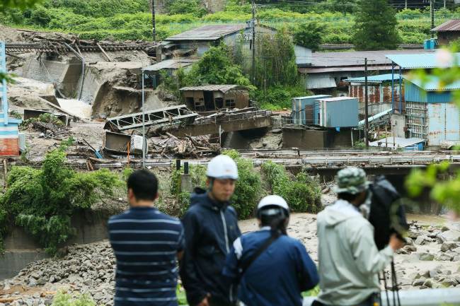 A TV crew works near the Nashizawa river at Nagiso town in Nagano prefecture, central Japan, Thursday, following a mudslide.   AFP-Yonhap