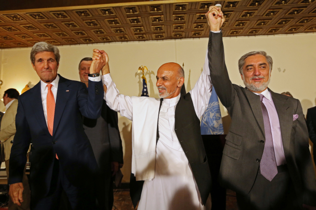 U.S. Secretary of State John Kerry (left) and Afghanistan’s presidential candidates, Ashraf Ghani (center) and Abdullah Abdullah, raise their hands during a joint press conference in Kabul on Saturday.   AP-Yonhap