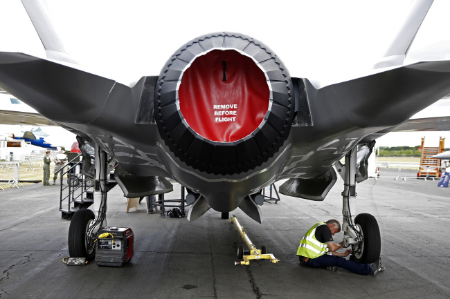 A worker checks the landing gear of a model of a F-35 Lightning II joint strike fighter jet, produced by Lockheed Martin Corp., as it stands on display prior to the opening of the Farnborough International Airshow in England on Sunday.   Bloomberg