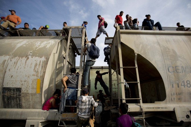 Central American migrants climb on a northbound train during their journey toward the U.S.-Mexico border, in Ixtepec, Mexico, Sunday.   AP-Yonhap