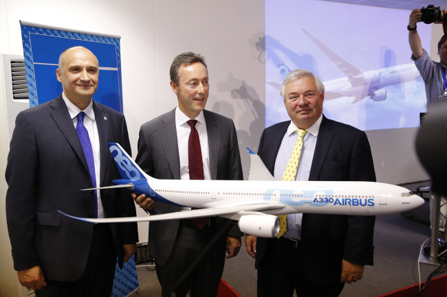 Eric Schulz (left), president of civil large engines at Rolls Royce Holdings Plc; Fabrice Bregier (center), chief executive officer of Airbus; and John Leahy, chief operating officer of Airbus Group NV, pose with a model Airbus A330-800neo aircraft, during a news conference during the Farnborough International Airshow in Farnborough, England, Monday.    Bloomberg
