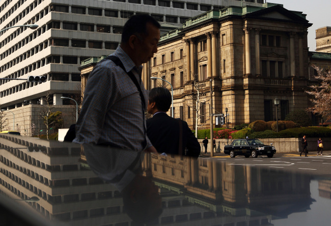 Pedestrians walk past the Bank of Japan headquarters in Tokyo.   Bloomberg