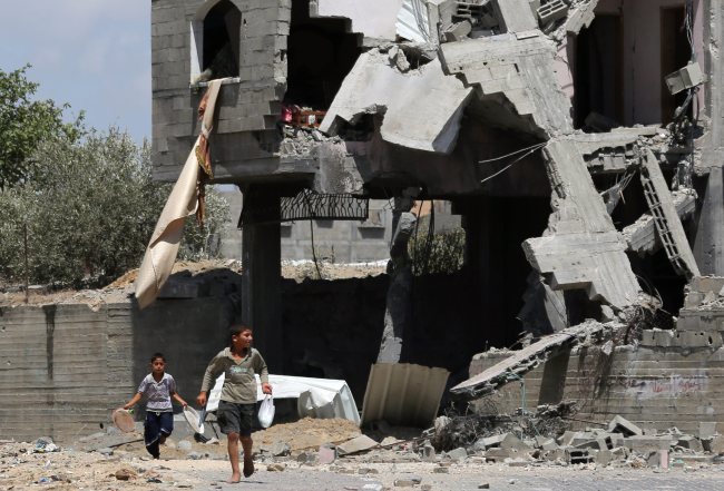 Palestinian youths walk past a destroyed house in Beit Lahiya in the northern part of the Gaza Strip on Monday. Israel bombed 40 more targets in the Gaza Strip and Palestinian militants launched at least 20 rockets across the border, despite a call by the U.N. secretary-general for a truce. The death toll rose to over 170 on the seventh day of the Israeli offensive, with more than 1,200 wounded, a Gaza Health Ministry spokesman said.   EPA-Yonhap