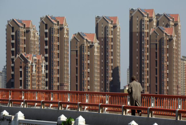 A pedestrian walks on a bridge in front of residential buildings at Sino-Singapore Tianjin Eco-city in Tianjin, China.   Bloomberg