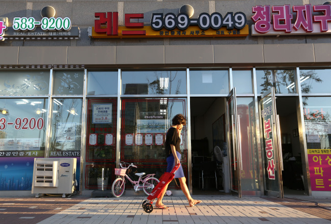 A pedestrian walks past real estate agencies at Cheongna International City in Incheon.   Bloomberg.