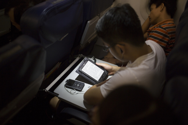 A passenger reads on an Amazon.com Inc. Kindle tablet on board a VietJet Air aircraft at Noi Bai International Airport in Hanoi, Vietnam. Bloomberg