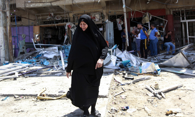Civilians inspect the site of a bomb attack in the Jihad neighborhood in Baghdad on Saturday.   AP-Yonhap