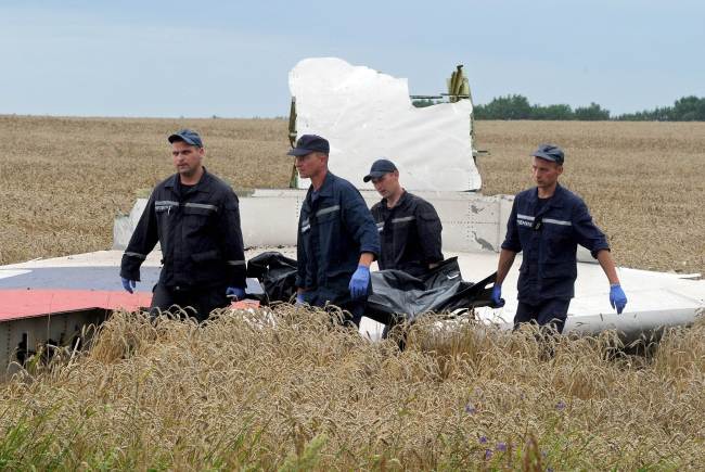 Ukrainian rescue workers walk past a piece of wreckage as they carry the body of a victim on a stretcher at the site of the crash of a Malaysia Airlines plane carrying 298 people from Amsterdam to Kuala Lumpur in Grabove, in rebel-held east Ukraine, Saturday.   AFP-Yomhap