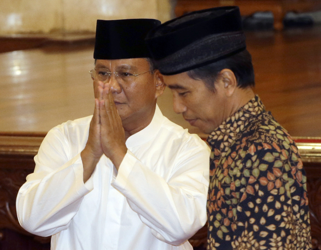 Indonesian presidential candidate Prabowo Subianto (left) gestures upon arriving to break his fast with his opponent Joko Widodo at the State Palace in Jakarta on Sunday.   AP-Yonhap
