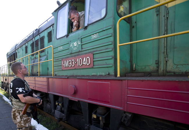 An armed pro-Russian rebel speaks to the driver of a refrigerated train loaded with the bodies of victims, in Torez, eastern Ukraine, 15 kilometers from the crash site of Malaysia Airlines Flight 17, Sunday.   AP-Yonhap
An armed pro-Russian rebel speaks to the driver of a refrigerated train loaded with the bodies of victims, in Torez, eastern Ukraine, 15 kilometers from the crash site of Malaysia Airlines Flight 17, Sunday.   AP-Yonhap