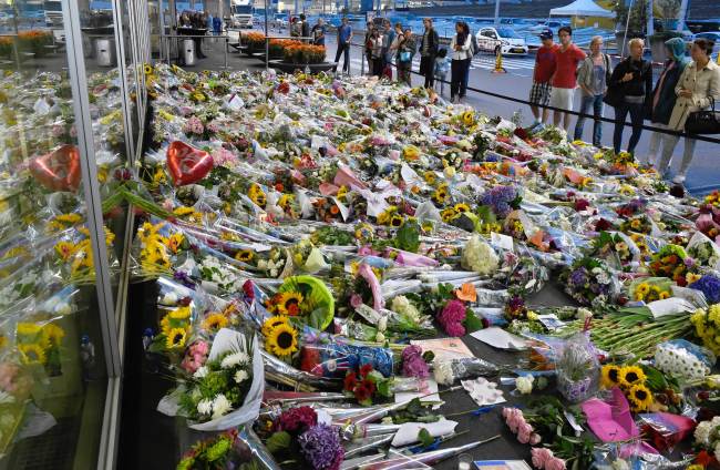 People look at flowers placed in remembrance of the victims of the Malaysia Airlines Flight 17 crash, at Schiphol Airport, near Amsterdam, Monday.   AFP-Yonhap