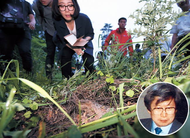 Investigators and journalists look at a lock of hair and bone fragments that police say were torn from the dead body of runaway Yoo Byung-eun (in circle) at a farm in Suncheon, South Jeolla Province, Tuesday. (Yonhap)