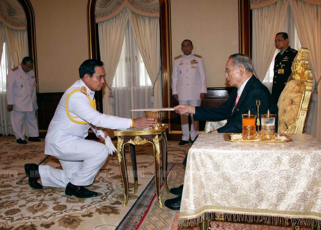 Army chief Gen. Prayut Chan-O-Cha (left) receives the interim constitution from King Bhumibol Adulyadej at the royal palace in Hua Hin, Thailand, Tuesday.   AFP-Yonhap