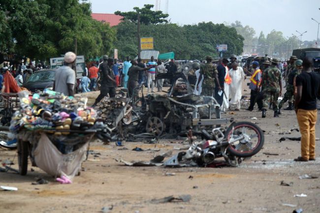 People stand near a wrecked car after a bomb exploded in Kaduna, north of Nigeria, Wednesday.   AFP-Yonhap