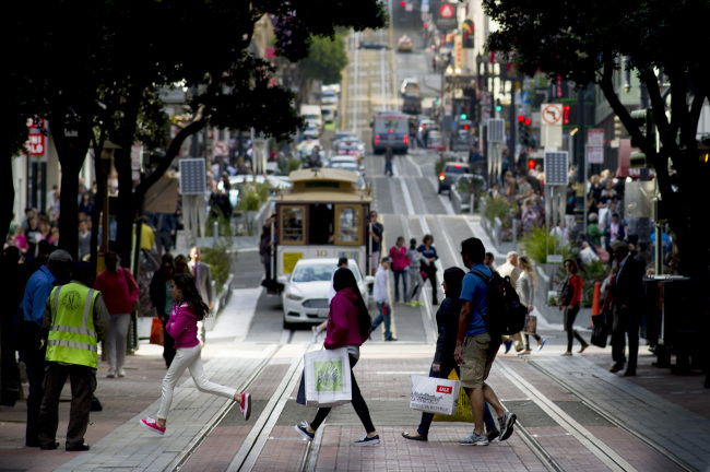 Pedestrians carry shopping bags while crossing a street in San Francisco, California.   Bloomberg
Pedestrians carry shopping bags while crossing a street in San Francisco, California.   Bloomberg