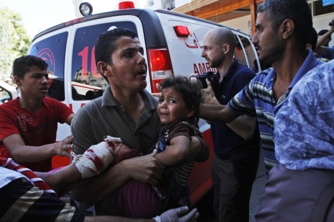 A Palestinian man carries a child wounded in an Israeli strike on a U.N. school in Beit Hanoun in the northern Gaza Strip on Thursday.   AP-Yonhap
