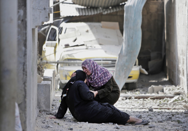 Palestinian Manal Keferna (right) cries with her sister-in-law Najwa Keferna upon their return to the family house destroyed by Israeli strikes in Beit Hanoun, northern Gaza Strip, Saturday. Thousands of Gaza residents who had fled Israel-Hamas fighting streamed back to devastated border areas during a lull Saturday to find large-scale destruction: Scores of homes were pulverized, wreckage blocked roads and power cables dangled in the streets. (Related story on Page 5)   AP-Yonhap