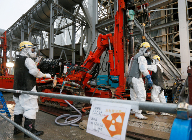 Workers wearing protective clothing and masks conduct operations for building a frozen underground wall surrounding the crippled reactor buildings at Tokyo Electric Power Co.'s (Tepco) Fukushima Dai-ichi nuclear power plant in Okuma, Fukushima Prefecture, Japan, on Wednesday, July 9, 2014. All of Japan's 48 operable commercial reactors are idled for safety assessments after the accident at the Fukushima plant. Photographer: Kimimasa Mayama/Pool via Bloomberg
Workers conduct operations for building a frozen underground wall surrounding the crippled reactor buildings at Tokyo Electric Power Co.’s Fukushima Dai-ichi nuclear power plant.   Bloomberg