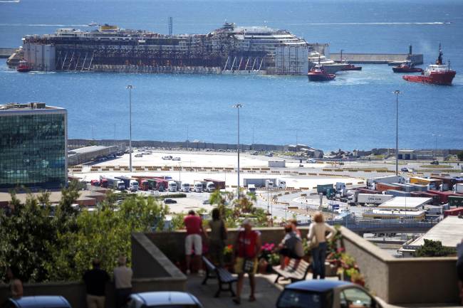 People watch as the refloated wreck of the Costa Concordia cruise liner is towed to the Italian port of Genoa on Sunday.   AFP-Yonhap
