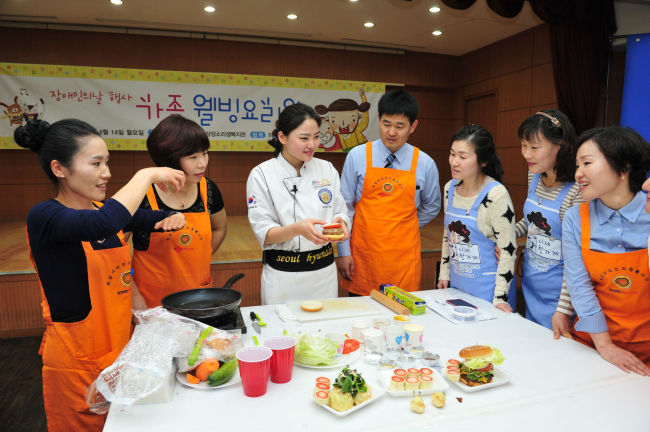 Amway employees and the company’s independent business owners participate in a cooking class with visually impaired people at a welfare facility in Seoul.   Amway Korea