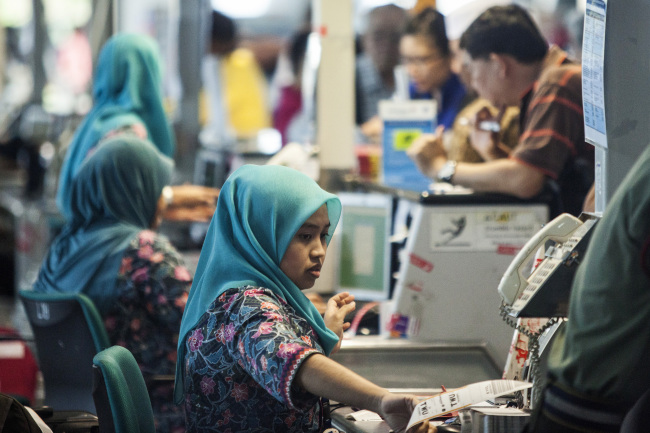 Members of Malaysian Airline System ground staff serve passengers at check-in counters at Kuala Lumpur International Airport in Sepang.   Bloomberg