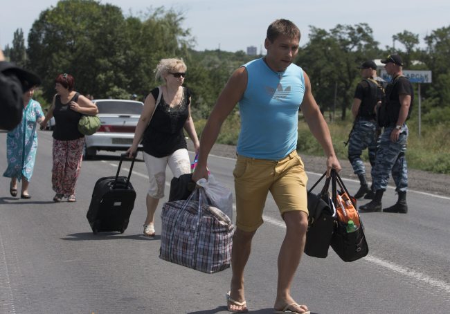 Self-proclamed Donetsk People’s Republic policemen watch refugees fleeing Shakhtarsk, Donetsk region, eastern Ukraine, Monday.   AP-Yonhap