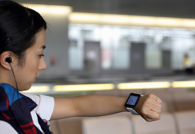 A Japan Airlines staff member checks her email on an LG Electronics smart watch as she works at the departure counter at Haneda Airport in Tokyo.   Bloomberg