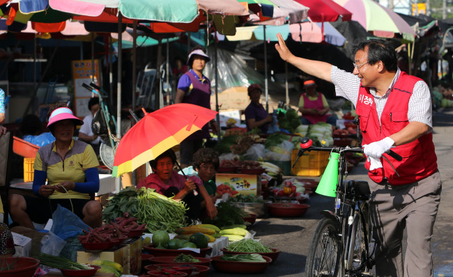 Lee Jung-hyun greets citizens in Suncheon, South Jeolla Province, on his bicycle on Thursday. Lee, a member of the Saenuri Party, defeated his liberal competitor in Wednesday’s by-elections to become the first conservative lawmaker to be elected in a Jeolla constituency since 1996.   Yonhap