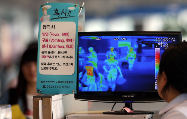 A quarantine officer monitors travelers’ body temperatures at Incheon International Airport on Monday.   Yonhap