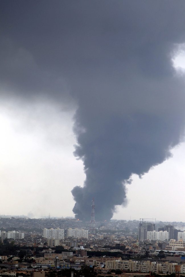Smoke fills the sky over Tripoli after rockets fired by one of Libya’s militias struck and ignited a tank in the capital’s main fuel depot Sunday.   EPA-Yonhap