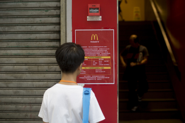 A man reads a food safety information sign displayed outside a McDonald’s in Hong Kong.   Bloomberg