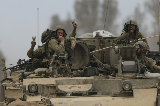 Israeli reserve soldiers are seen on the top of an armored personnel carrier retunring to Israel from Gaza Strip, southern Israel, Monday.   AP-Yonhap