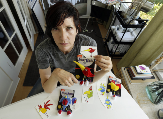 Artist Juli Adams poses for a photo in her home in Seattle on Tuesday, with some of her original drawings that a line of plush pet toys called “Angry Birds” were based on.   AP-Yonhap