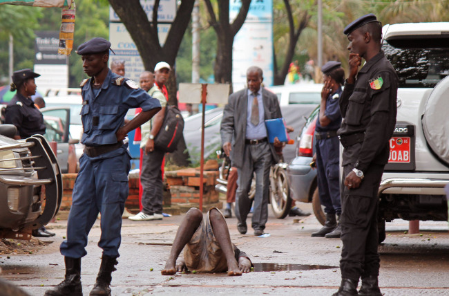 Guinean Police secure the area around a man who collapsed in a puddle of water on the street, while people avoid him for fear that he is infected with the Ebola virus in the city of Conakry, Guinea, Wednesday. The man lay in the street for several hours before being taken to an Ebola control center for assessment. (Related stories on Pages 2, 6)   AP-Yonhap